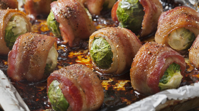 Bacon-wrapped Brussels sprouts in a foil-lined pan
