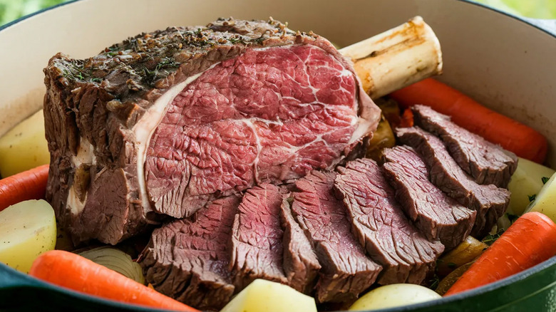 Cooked, sliced prime rib roast with carrots, potatoes, and onions