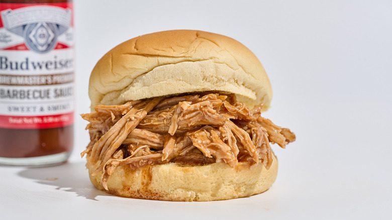 Bottle of Sweet and Smoky sauce next to a pulled pork sandwich