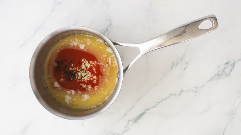A medium saucepan with buffalo sauce ingredients added to melted butter.