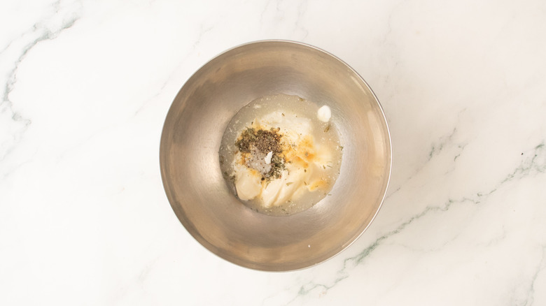 A medium metal bowl filled with ranch dressing ingredients.