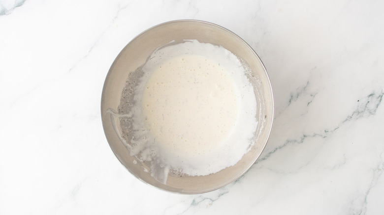 A medium metal bowl containing ranch dressing.
