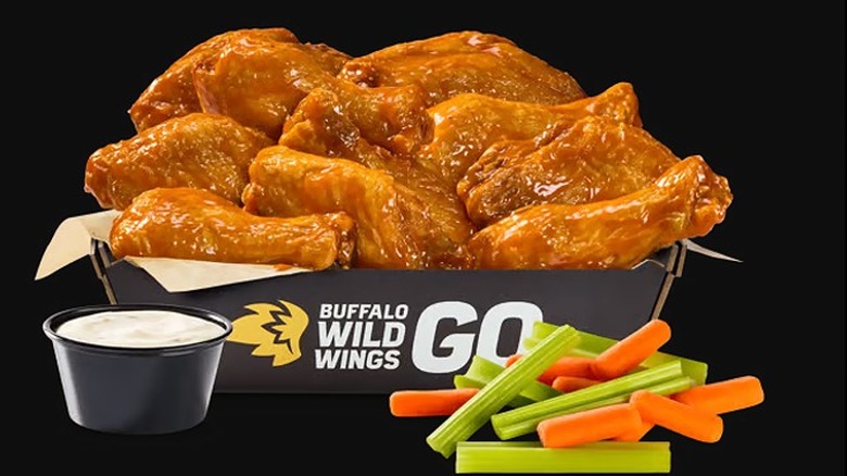 Buffalo Wild Wings Bone-In Wings with sauce and vegetables on a black background