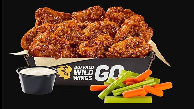 Buffalo Wild Wings Boneless Wings with sauce and vegetables on a black background