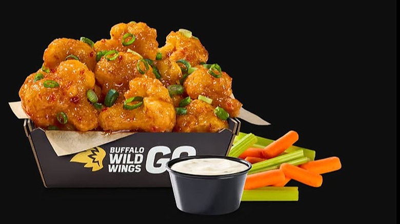 Buffalo Wild Wings Cauliflower Wings with sauce and vegetables on a black background