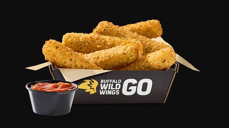 Basket of Buffalo Wild Wings Mozzarella Sticks with a container of marinara sauce on a black background
