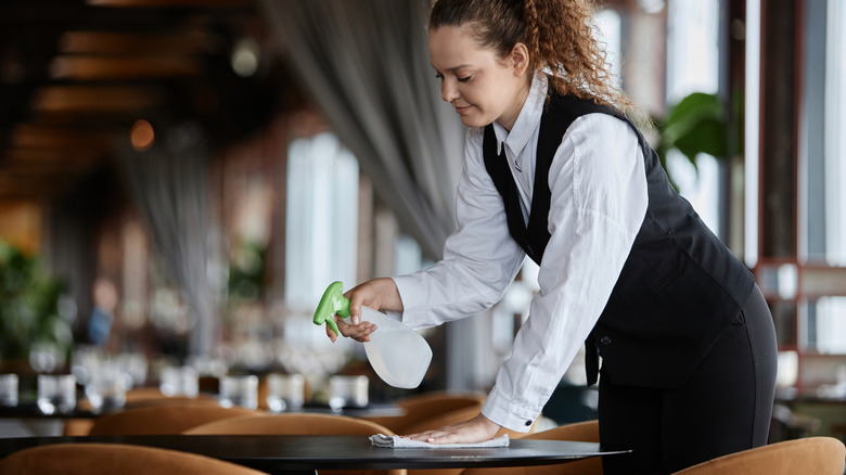 Young woman wiping down a table in a restaurant