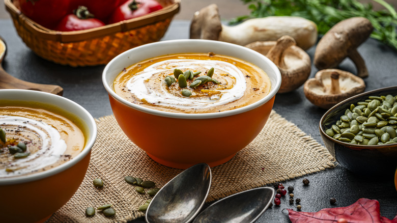 A bowl of orange soup topped with nuts