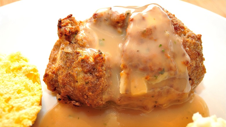 Mini meatloaf covered in brown gravy on a white plate