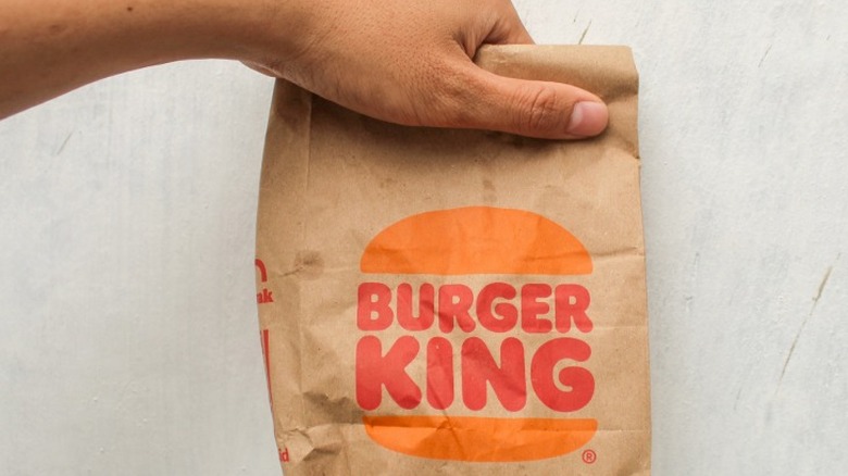A hand holding a Burger King food bag.