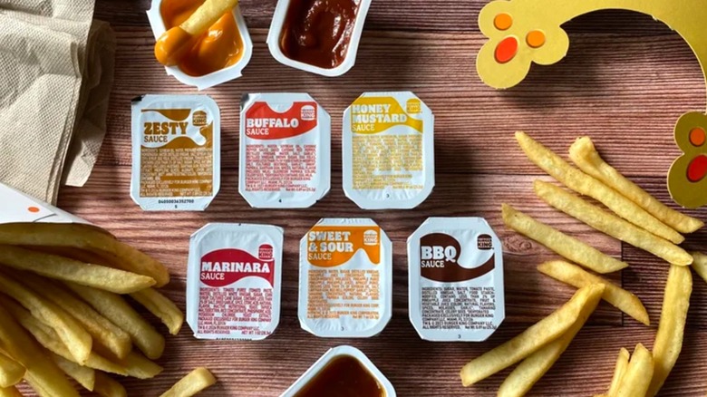 All six of Burger King's sauce options surrounded by fries, napkins, and a crown