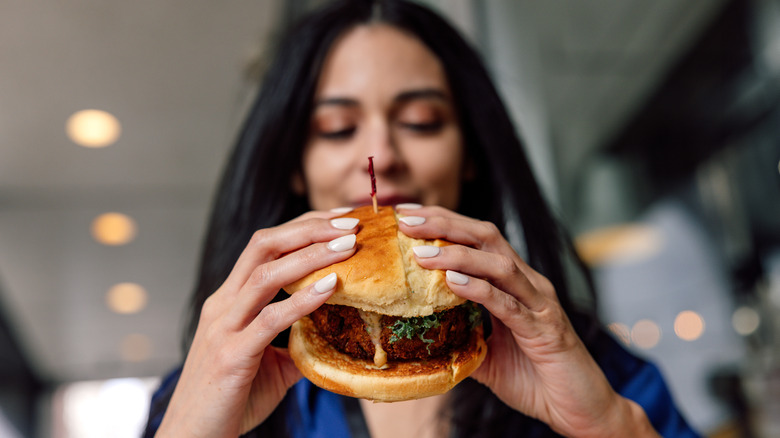 woman enjoying a stacked burger.