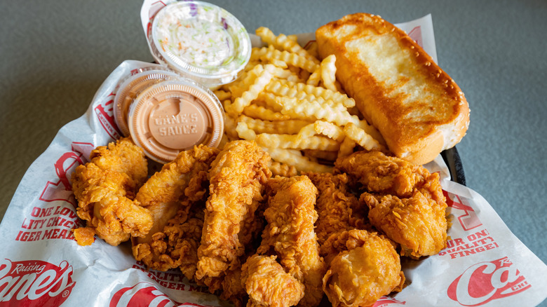 A combo meal from Raising Cane's with chicken tenders, crinkle-cut fries, Texas toast, and Cane's sauce
