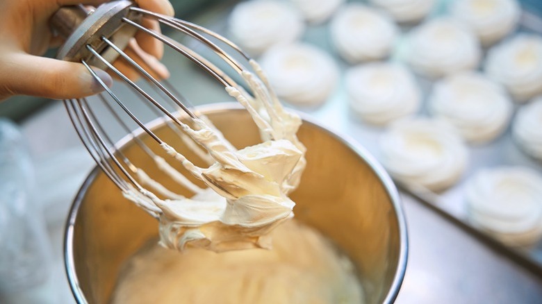 White whipped butter frosting in mixer.