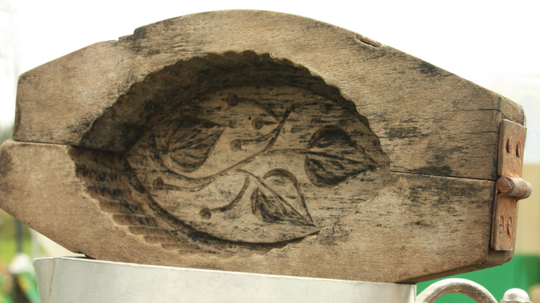 A wooden butter mold with fluted edges and a leaf design