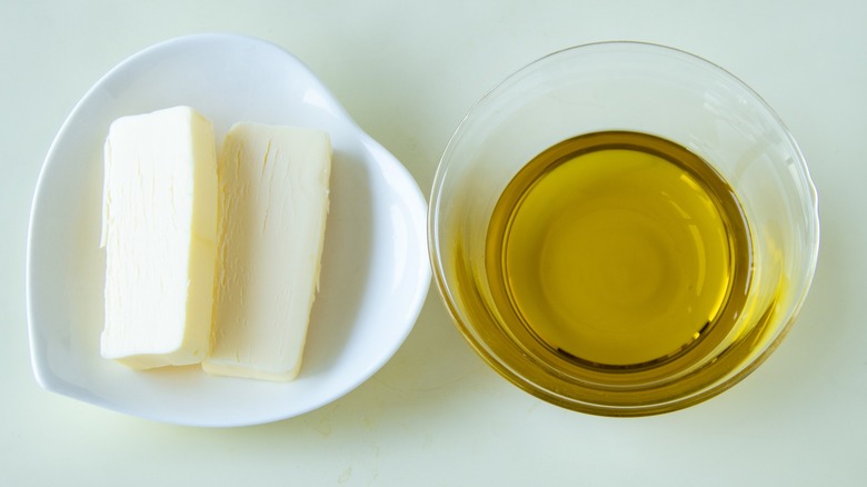 A dish of butter sticks beside a dish of cooking oil photographed from above.