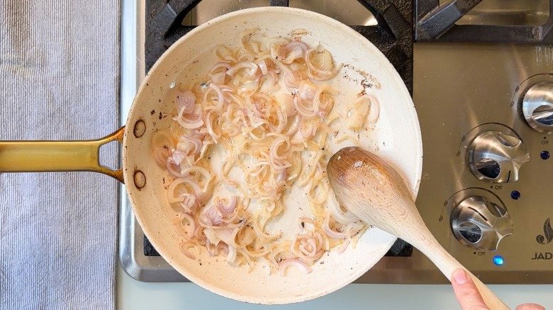 Sliced shallots cooking in bacon fat in skillet