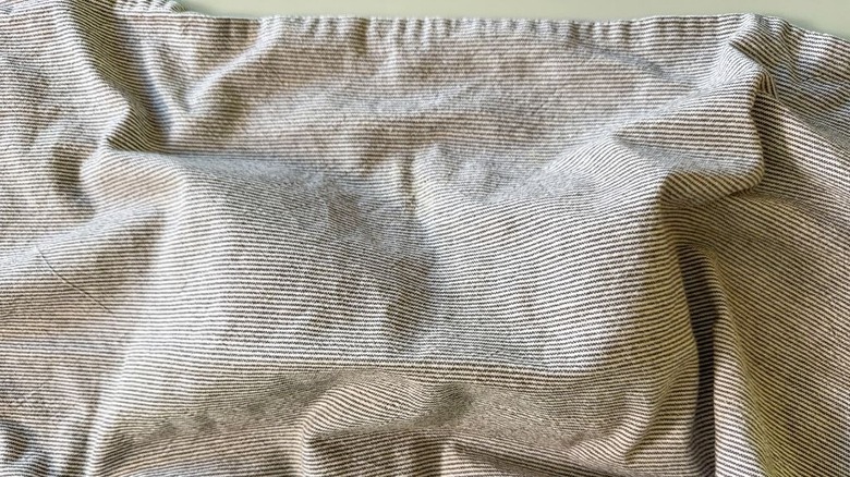 Kitchen towel over pizza dough balls on countertop