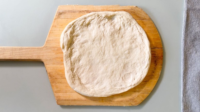 Hand-pulled pizza dough on floured pizza peel