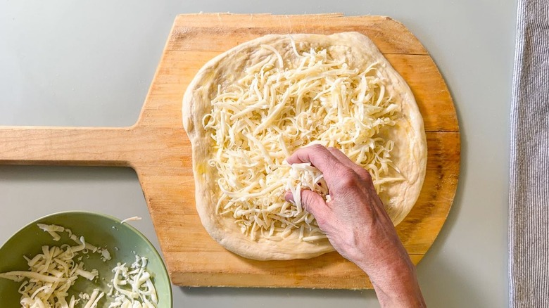 Adding shredded cheese to unbaked pizza crust