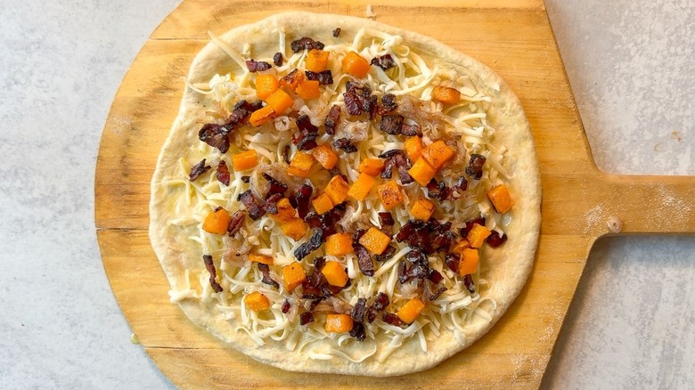 Unbaked butternut squash and maple bacon pizza on pizza peel
