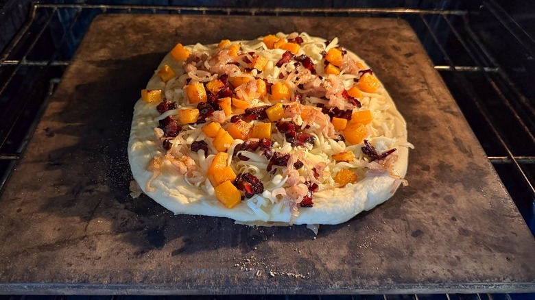 Butternut squash and maple bacon pizza baking on pizza stone in oven