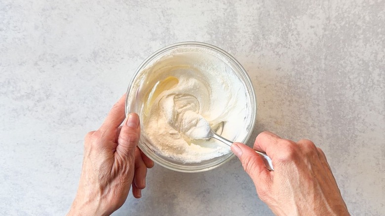 Whipping ricotta with a fork in a small glass bowl