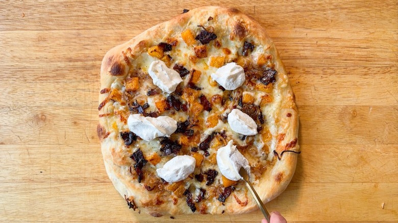 Adding spoonfuls of whipped ricotta to baked butternut squash and maple bacon pizza