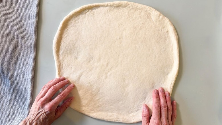 Hand-stretched pizza crust on countertop