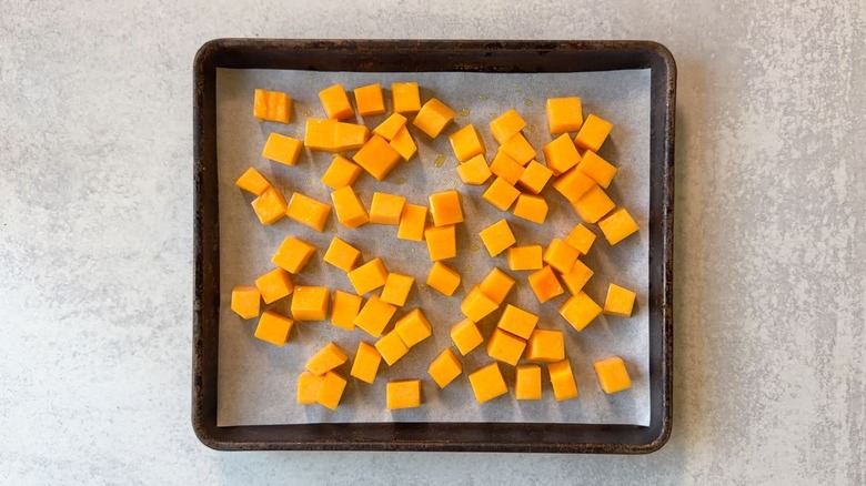 Oiled butternut squash cubes in single layer on parchment-lined baking sheet