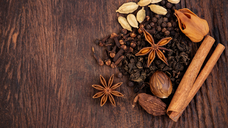 Herbs or spices in masala chai placed on an old wooden background.