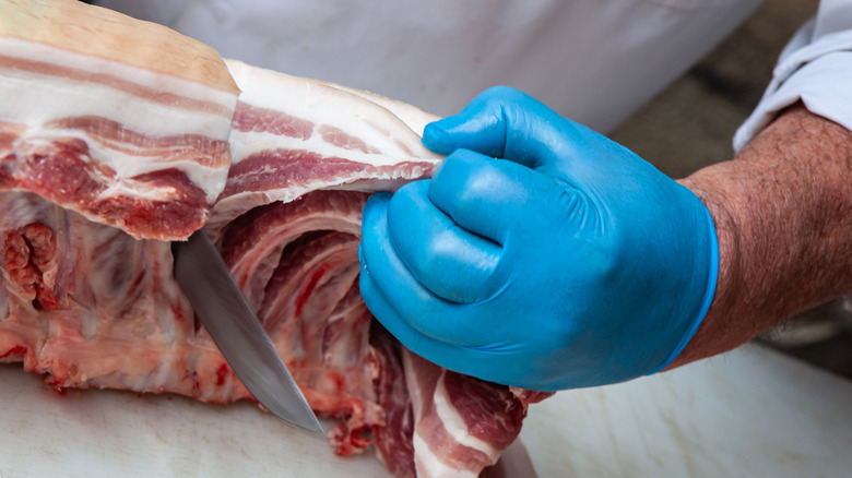 A butcher cutting chops from a rack of pork ribs