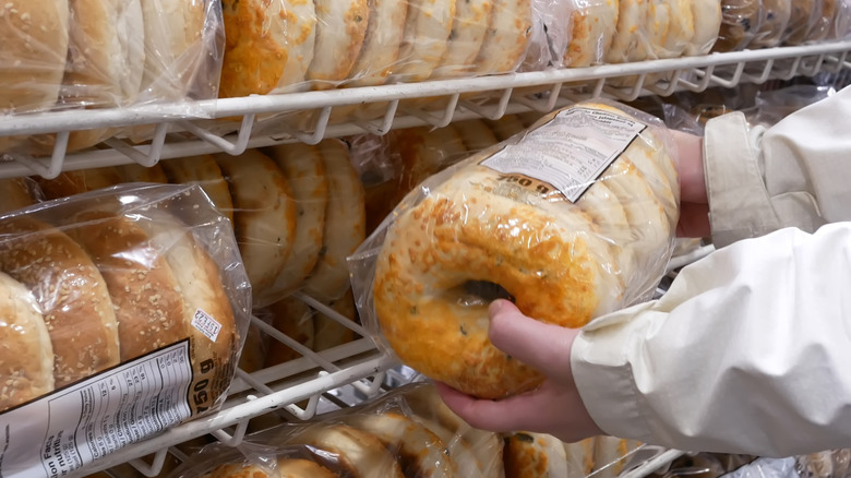A person's hands are seen holding a pack of bagels at a Costco