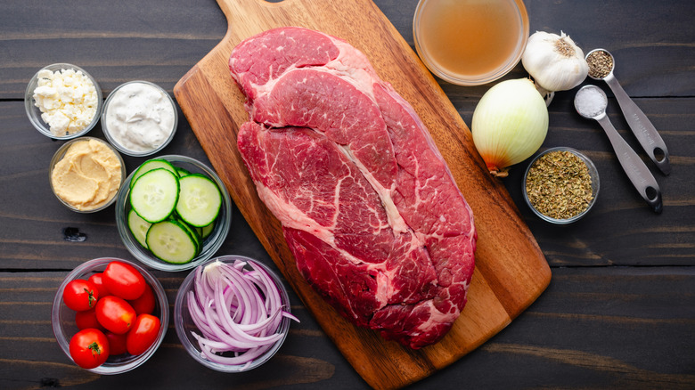 A marbled pot roast on a wooden cutting board photographed from above.