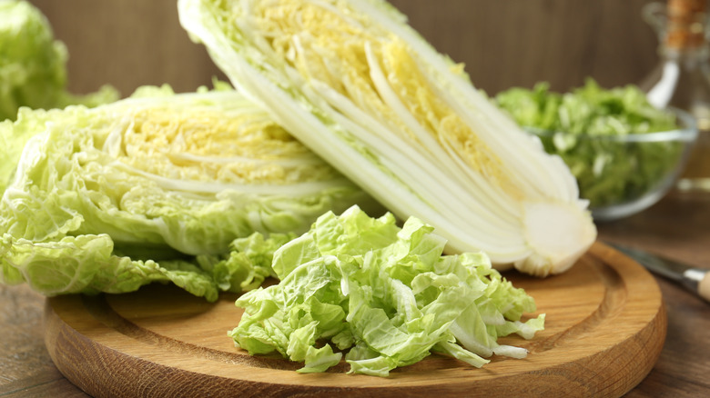 Halved and sliced napa cabbage on a wooden cutting board