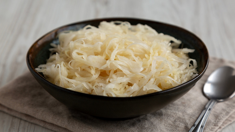 A bowl of sauerkraut next to a spoon