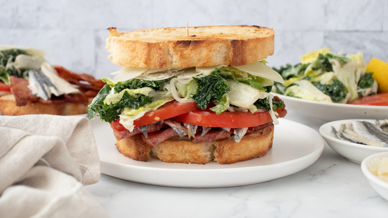 Side shot of a stacked BLT sandwich made with caesar salad ingredients