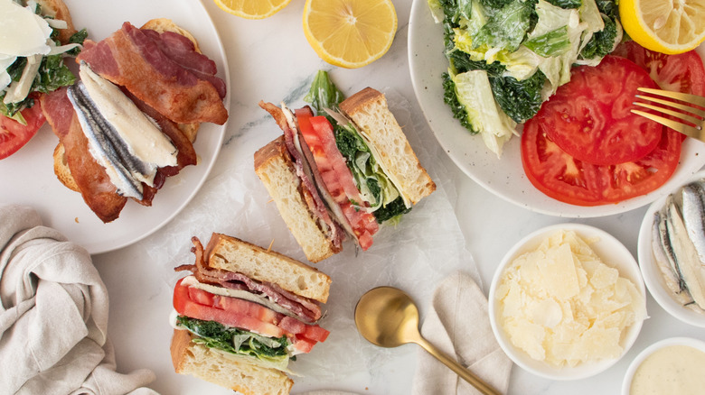 Overhead shot of caesar BLT sandwiches and toppings.