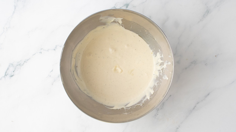 A metal bowl filled with caesar salad dressing