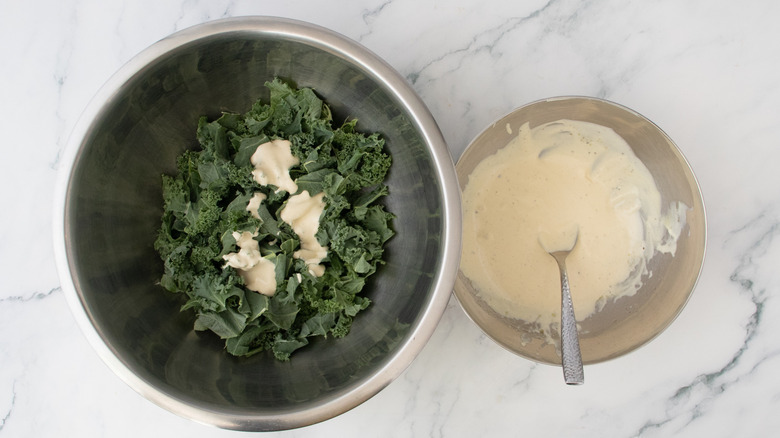 A large bowl filled with chopped kale drizzled with caesar dressing