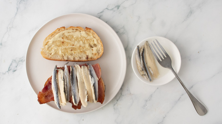 Bread slices topped with bacon and white anchovies