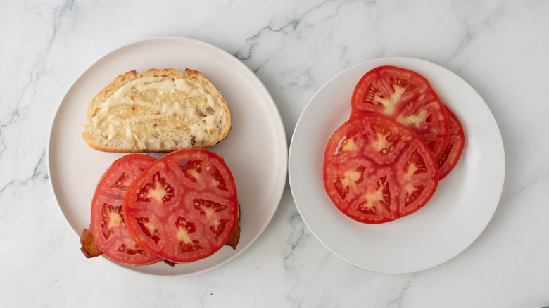 Bread slices topped with bacon, white anchovies and tomato slices
