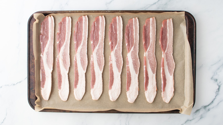 A large baking sheet topped with sliced bacon