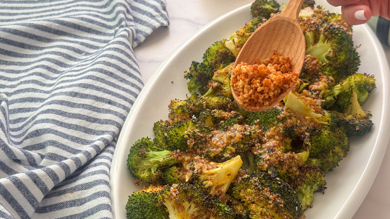 hand adding panko to broccoli