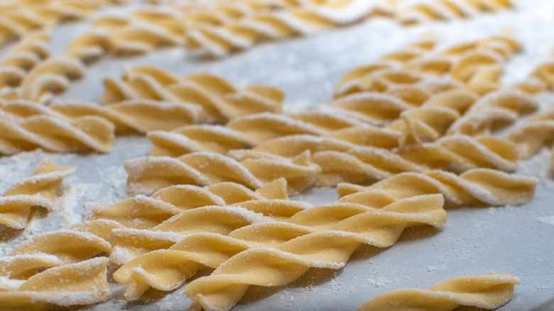 Egg noodles being made with a sprinkle of flour.