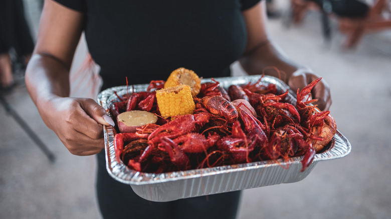 Person holding crawfish boil in tray