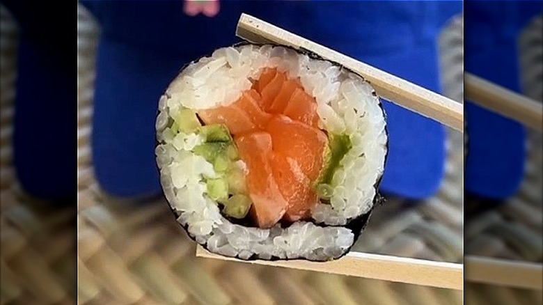 Chopsticks holding a piece of sushi.