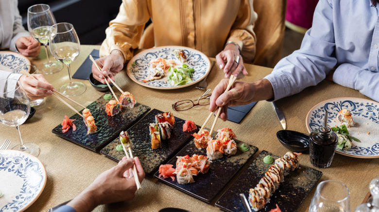 People around a dining table enjoying different kinds of sushi