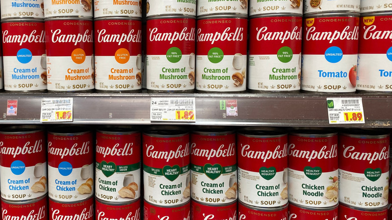 Rows of canned Campbell's soup lined on a grocery store shelf.