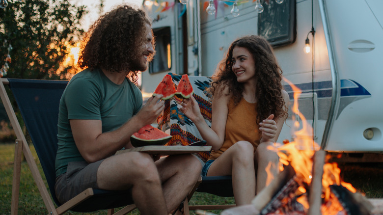 Couple eating watermelon by a fire